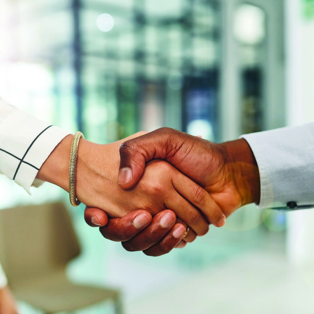 Two hands of what appear to be professionals, shaking hands as if making an agreement.