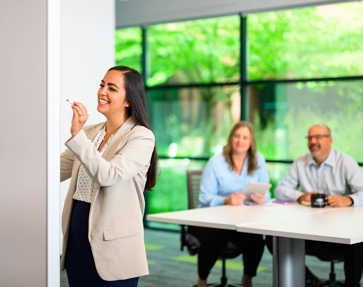 A woman writing on a whiteboard for other professionals