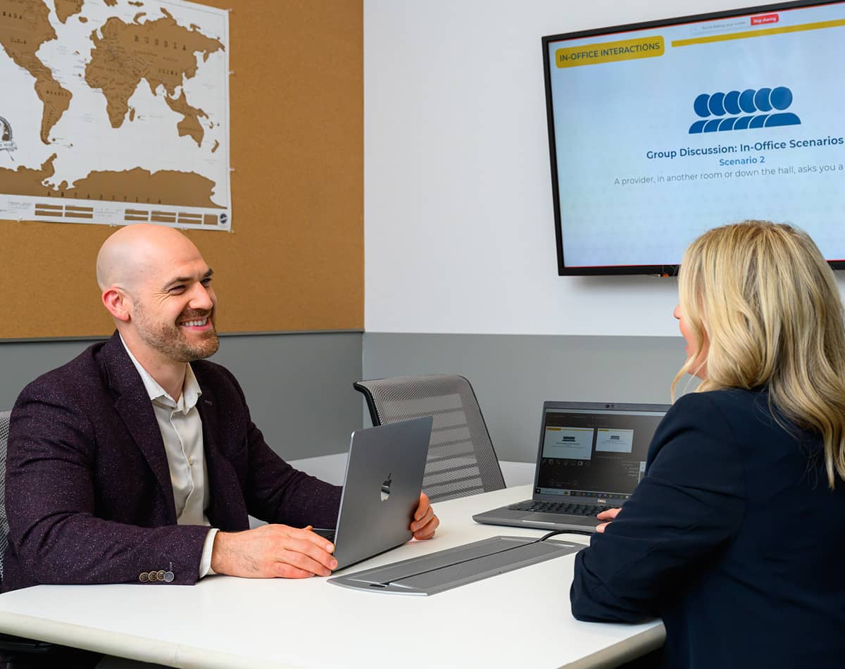 A man and woman meeting across the desk from each other