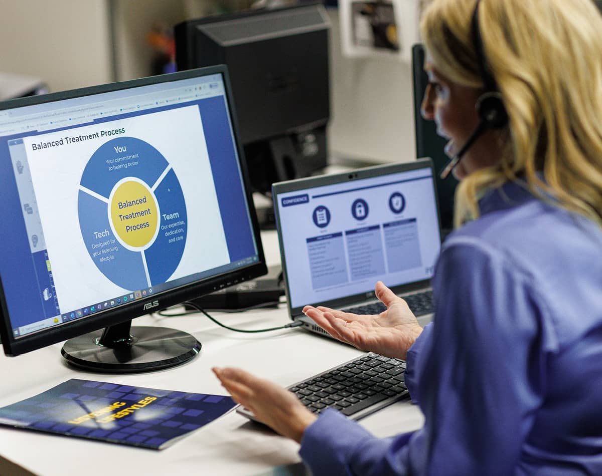 A woman looking at a computer with graphs on the screen.