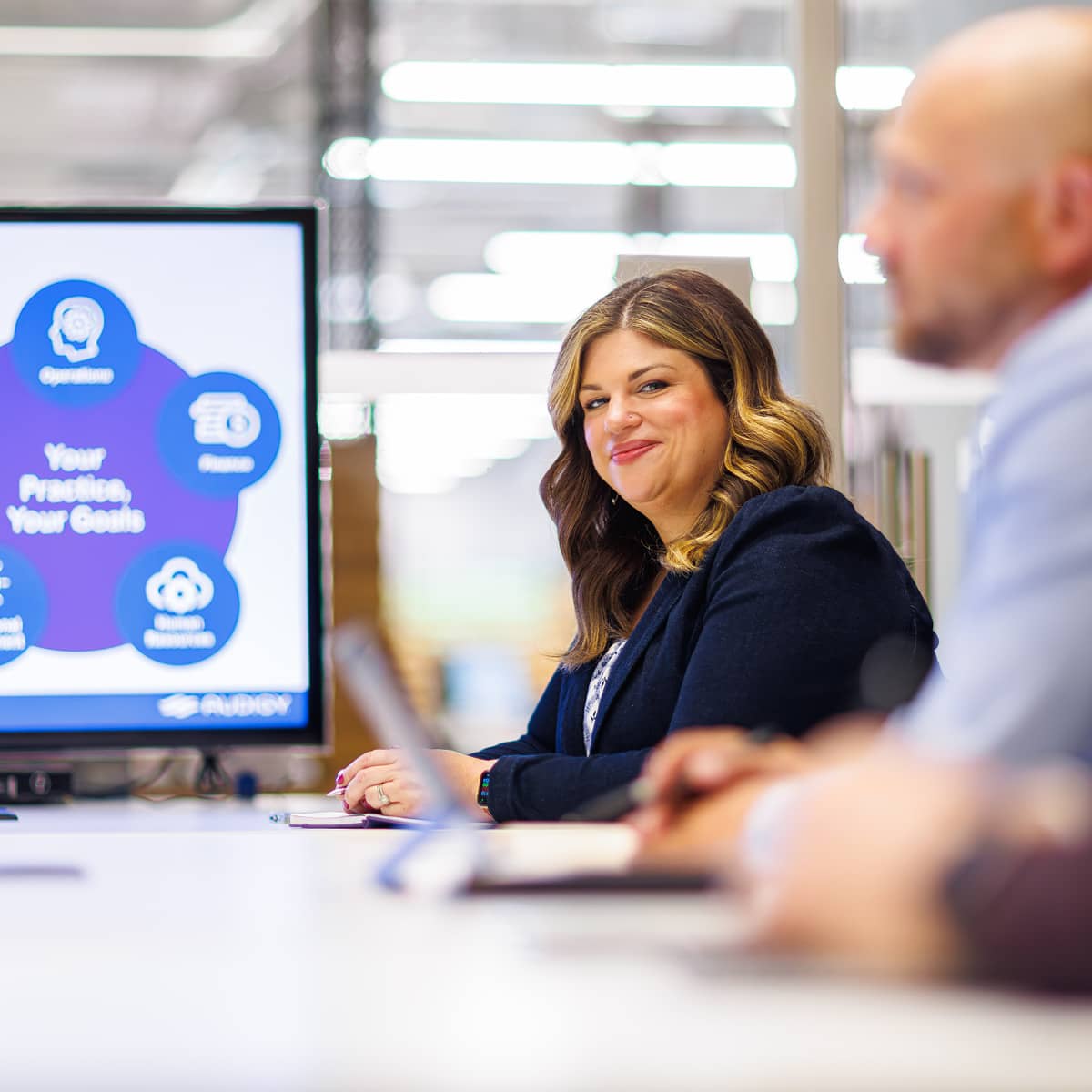 A professional woman and man sitting at a conference table