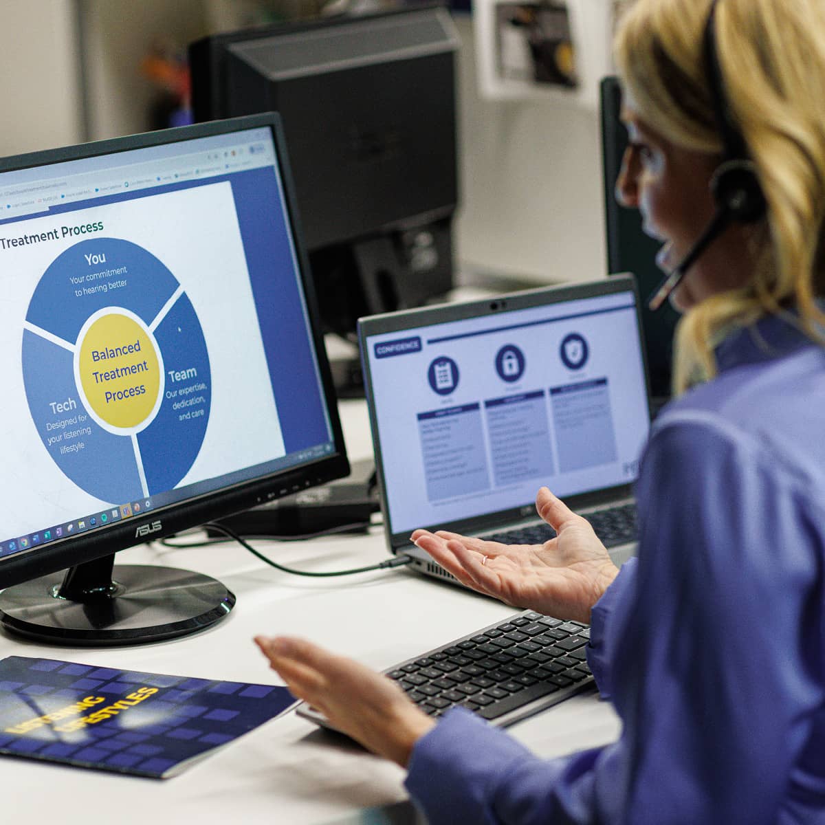 A woman looking at a computer with graphs on the screen.