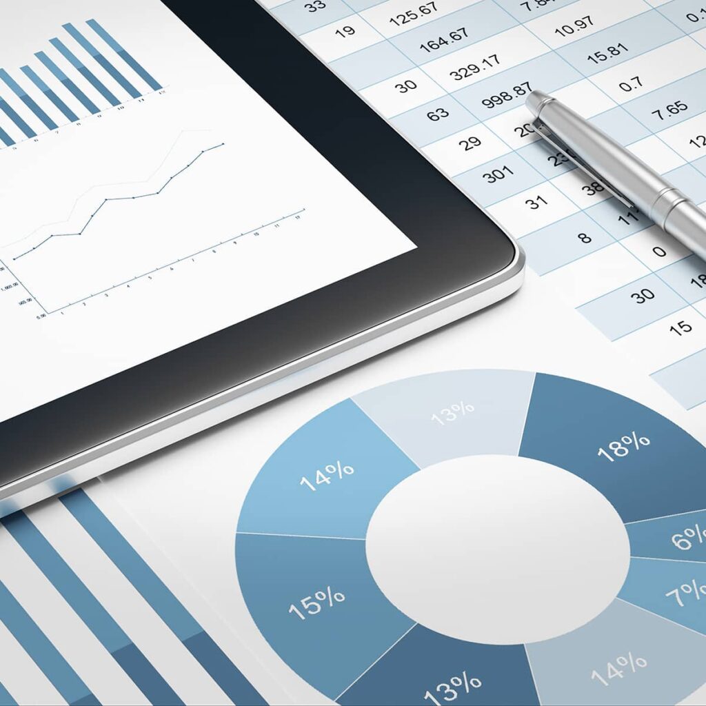 multiple printed papers and a tablet laying on a flat surface, showing a variety of charts and graphs.