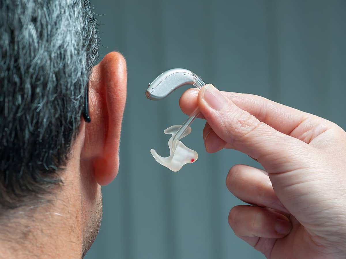 A professional installing a hearing aid in a patient's ear.