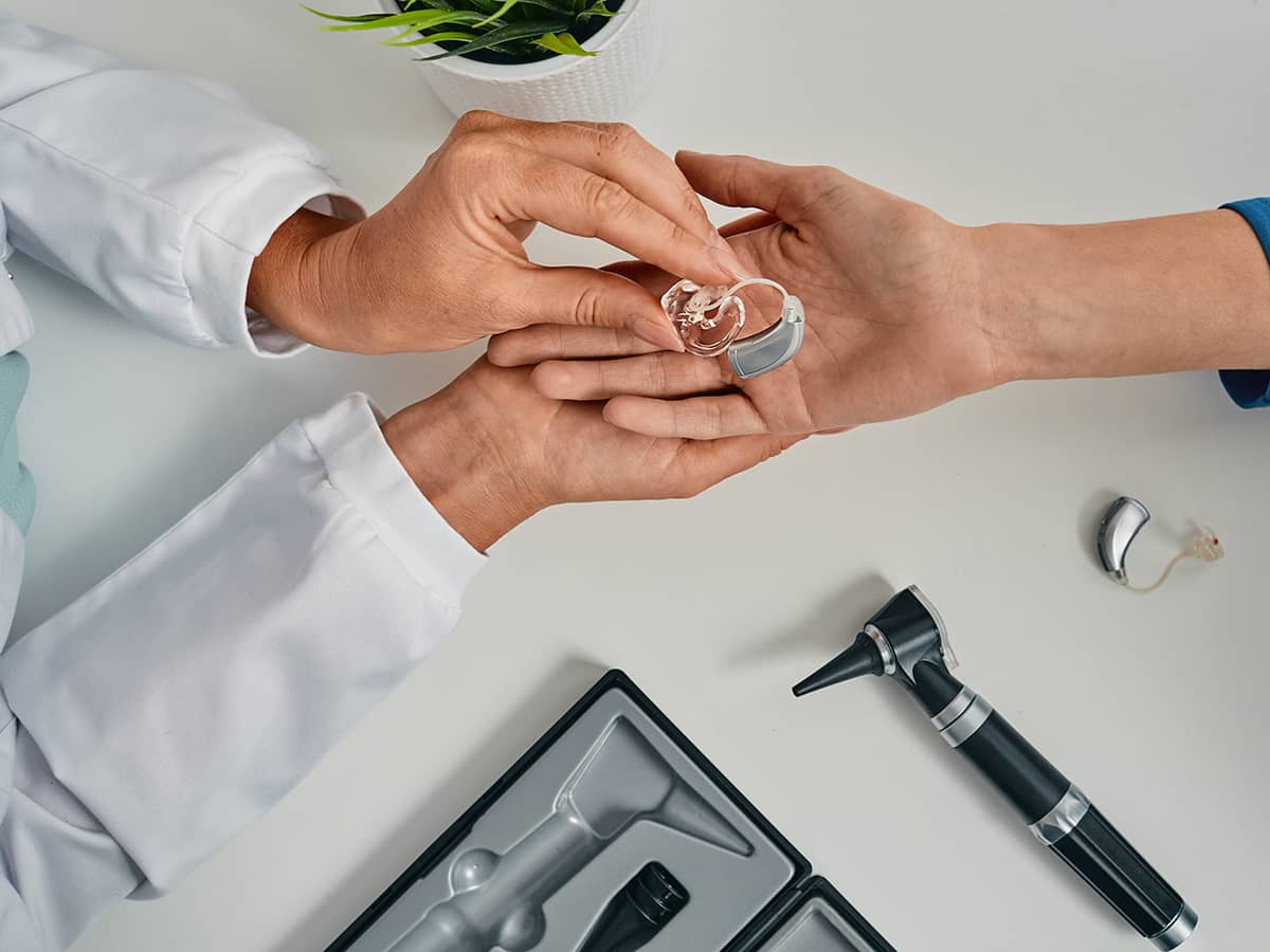 A doctor holding a patient's hearing aid.