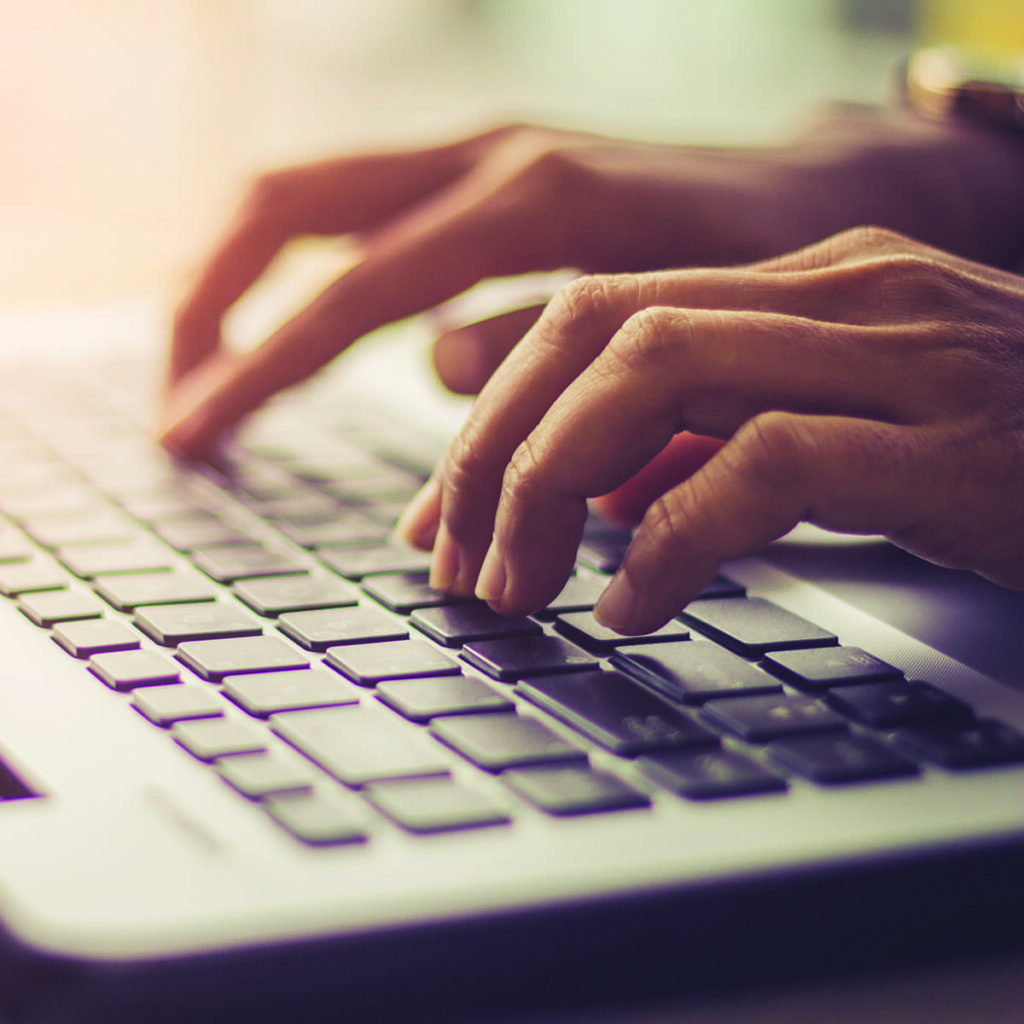 Hands typing on a laptop.