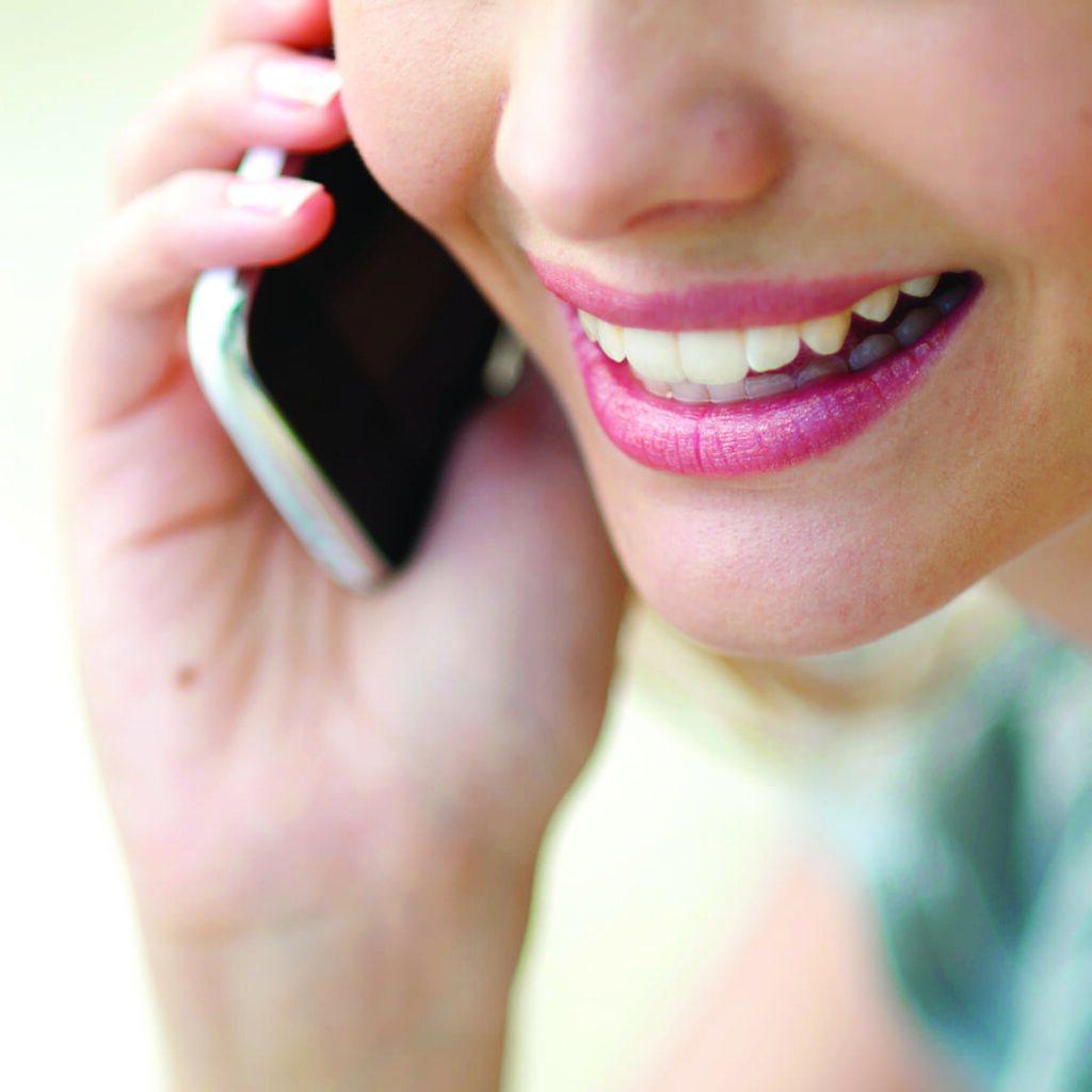 A woman talking on her cellphone, presumably contacting the hearing care practice.