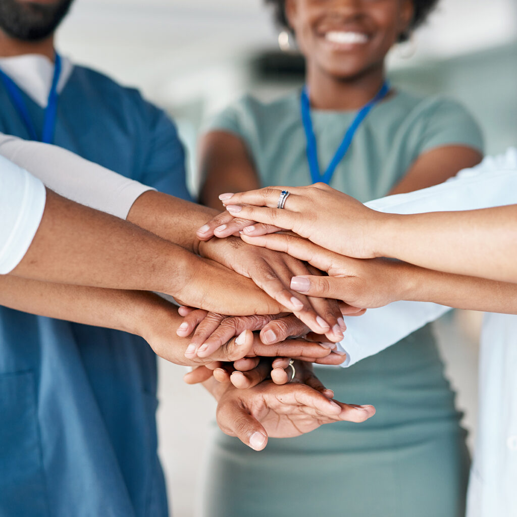 A team of hearing care professionals with their hands stacked as if doing a team cheer.